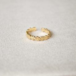 Goldener Blumenkranz Ring aus Edelstahl, liegend auf beigem Samtstoff