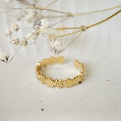 Goldener Blumenkranz Ring aus Edelstahl in einer hellbeigen Schale, dekoriert mit weißen getrockneten Blumen