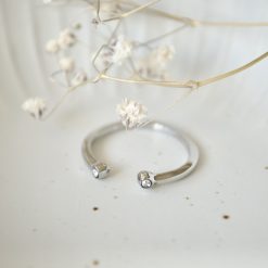 Silberfarbener Zirkonia-Ring in Schale mit weißen Trockenblumen